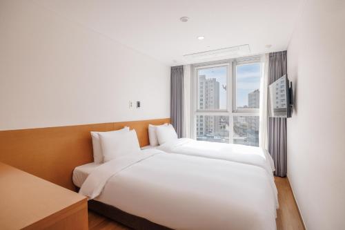 two beds in a hotel room with a window at Kenny Stay Busan Gijang in Busan