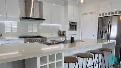 a white kitchen with a counter and stools at Beachside Oasis in Caves Beach