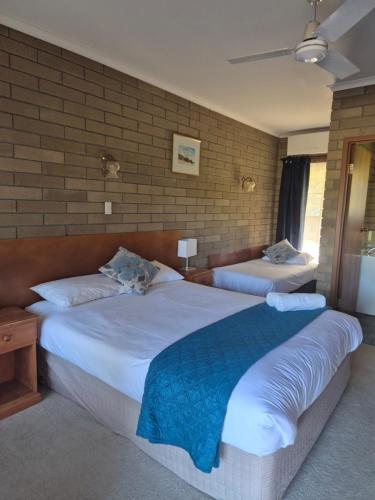a bedroom with two beds and a brick wall at Aristocrat Waurnvale in Geelong