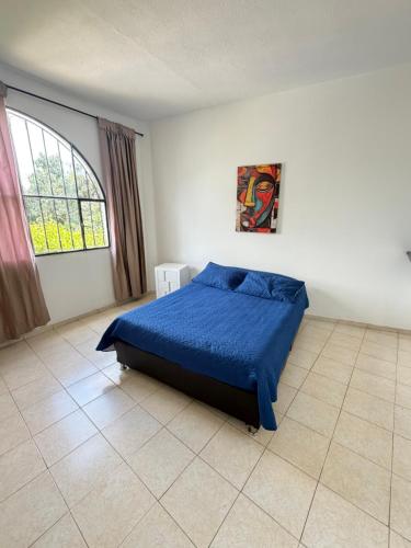 a bedroom with a bed with a blue comforter and a window at Villa Gabritali in La Mesa