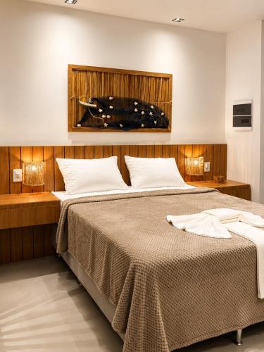 a bedroom with a large bed with white pillows at Estúdio Premium em Japaratinga - Unidade Coralli - Vila Naluri in Japaratinga