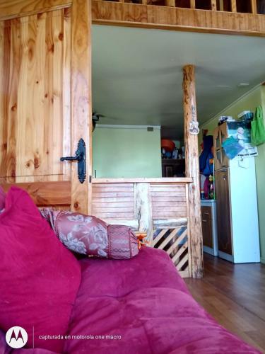 a bed in a room with a wooden wall at Cabaña Chaicura in Ancud