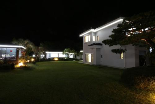 a white house with a yard at night at Maple Happy House Jeju in Jeju