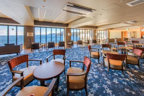 a conference room with tables and chairs and the ocean at Inatori Ginsuiso in Higashiizu