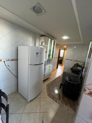 a kitchen with a white refrigerator in a room at apartamento aconchego 01 in Divinópolis