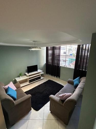 a living room with two couches and a television at apartamento aconchego 01 in Divinópolis