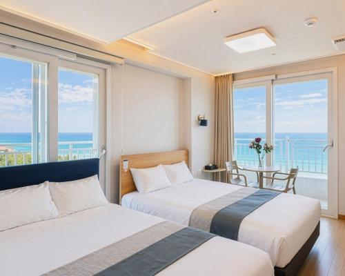 two beds in a hotel room with a view of the ocean at Gangneung Top Ocean in Gangneung