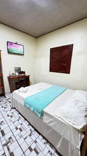 a bedroom with a bed and a desk in a room at Casarão da ilha in Ilha Cotejuba