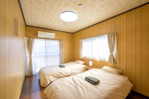 a bedroom with two beds and a window at もくハウス in Kamifukuoka