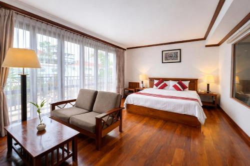 a bedroom with a bed and a couch and a table at Cheathata CTS Hotel Siem Reap in Siem Reap