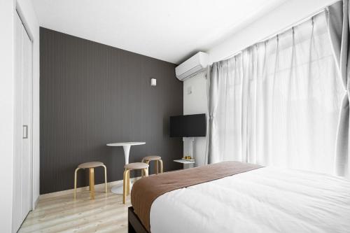 a bedroom with a bed and two chairs and a window at Grace Shintoshin in Saitama