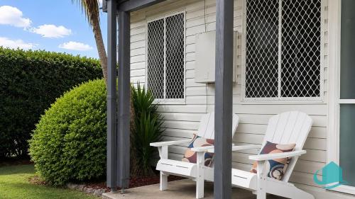 two white chairs sitting outside of a house at Beachside Cottage at Blacksmiths in Blacksmiths