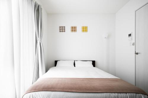 a bedroom with a bed with white walls and a window at Grace Shintoshin in Saitama