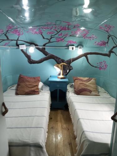 two beds in a room with a tree on the wall at Mostepa in Carpintería