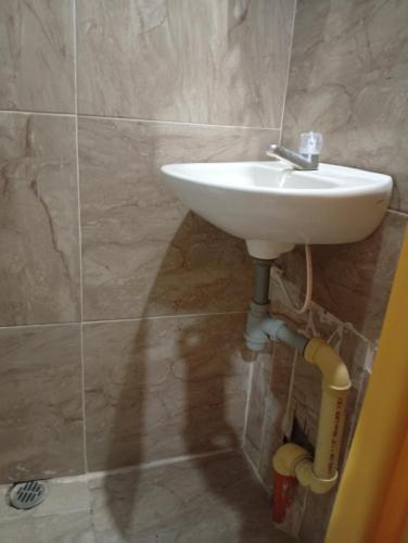 a bathroom with a white sink and a tiled wall at Casa Hotel el Sueño in Villavieja