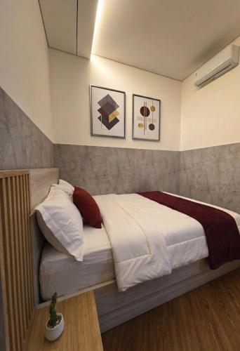 a bedroom with a bed with white sheets and red pillows at HOMY guesthouse 1 - dekat pintu TOL in Ciperna