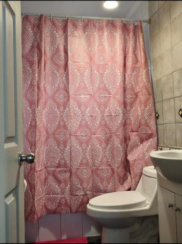 a bathroom with a red shower curtain and a toilet at Guacolda Coquimbo in Coquimbo