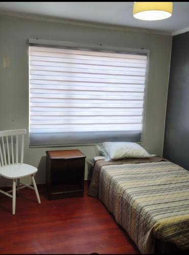 a bedroom with a bed and a window with a chair at Guacolda Coquimbo in Coquimbo