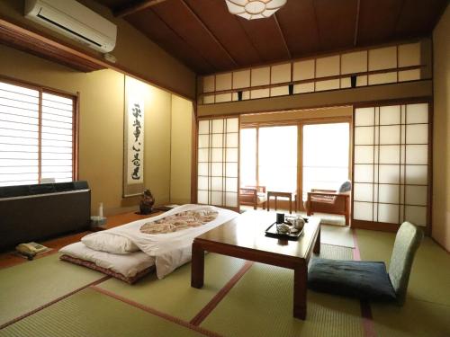 a room with a bed and a table in it at Sakaenoyu Ryokan in Matsumoto