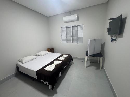 a white bedroom with a bed and a chair at Pousada In'capitólio in Capitólio