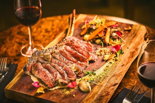 a steak on a cutting board next to a glass of wine at Apótek Hotel Reykjavík by Keahotels in Reykjavík