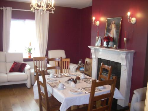 a dining room with a table and a fireplace at Golden Rose House in Knock