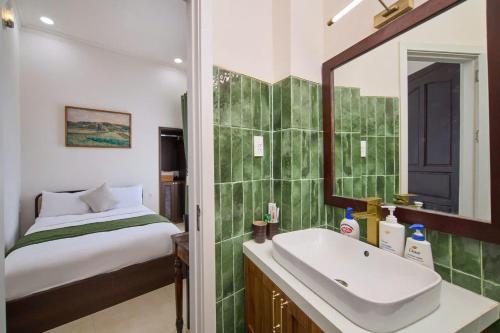 a bathroom with a sink and a bed and a mirror at APT Hotel Phan Rang in Phan Rang–Tháp Chàm