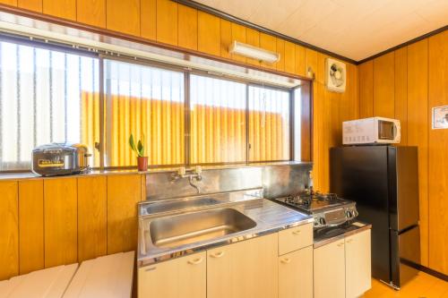 a kitchen with a sink and a refrigerator at もくハウス in Kamifukuoka