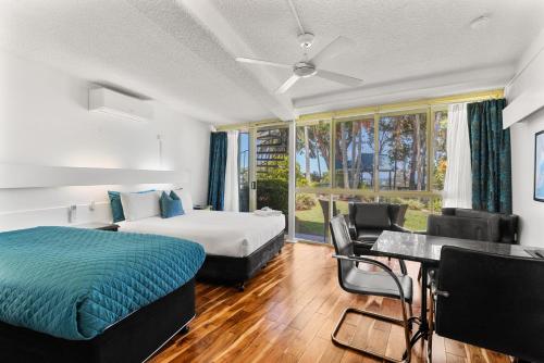 a bedroom with a bed and a table and chairs at Motel Miramar in Nambucca Heads