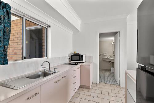 a white kitchen with a sink and a microwave at Motel Miramar in Nambucca Heads