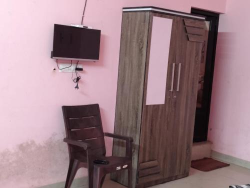 a wooden cabinet with a chair and a tv at Roamwander doublerooms in Vagamon