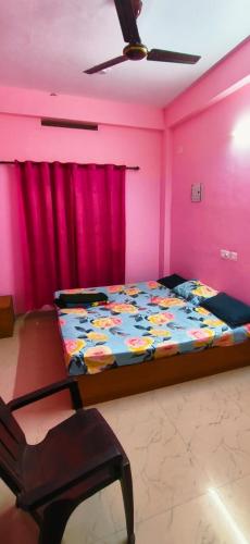 a bedroom with a bed with pink walls and a chair at Roamwander doublerooms in Vagamon