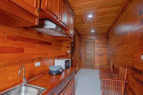 a kitchen with wooden walls and a sink and a microwave at Phetchalern serviced apartment in Vientiane