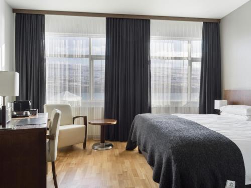 a hotel room with a bed and a chair and windows at Hotel Kea by Keahotels in Akureyri