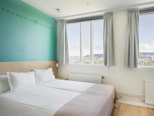 a bedroom with a bed and two windows at Reykjavik Lights Hotel by Keahotels in Reykjavík