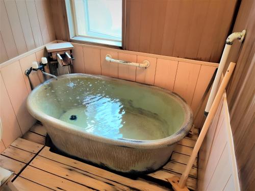 an old bath tub in a bathroom with a window at Yamaichi in Shizukuishi