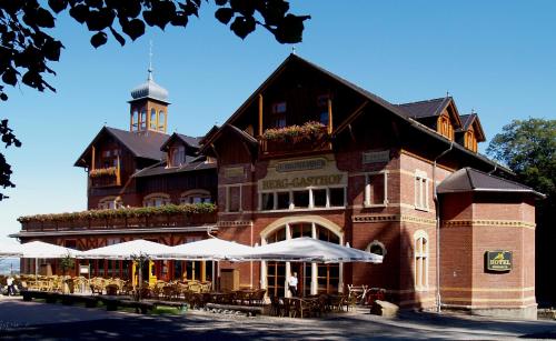 ein Gebäude mit Tischen und Sonnenschirmen davor in der Unterkunft Berg-Gasthof Honigbrunnen in Löbau