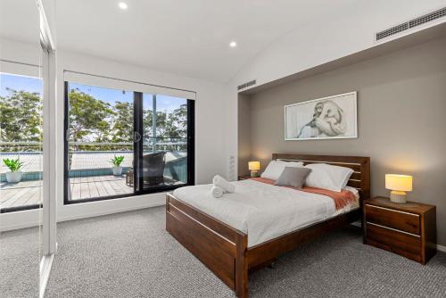 a bedroom with a bed and a large window at Bruma on Bowen - Opposite Shark Net Beach in Huskisson