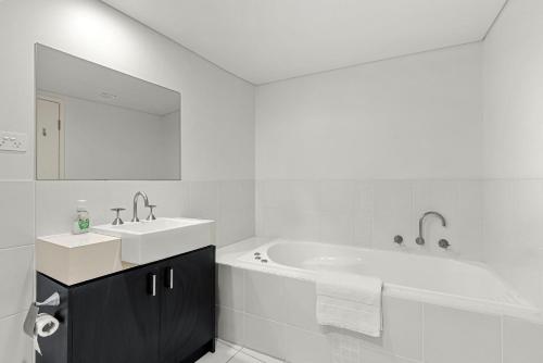 a white bathroom with a tub and a sink at Bruma on Bowen - Opposite Shark Net Beach in Huskisson