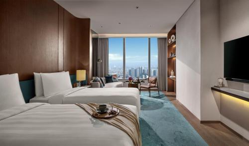 a hotel room with two beds and a television at Pan Pacific Jakarta in Jakarta