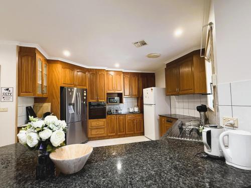a kitchen with wooden cabinets and a black counter top at Central Private Room - Stroll to ANU & City in Turner