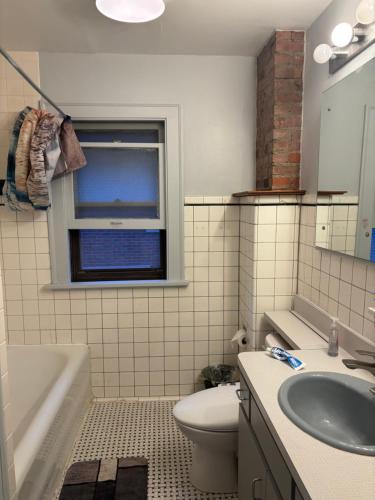 a bathroom with a sink and a toilet and a window at Updated cozy in central Cleveland in Cleveland