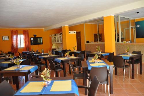 um restaurante com mesas e cadeiras azuis e paredes amarelas em Hotel Mare Blu em Lampedusa
