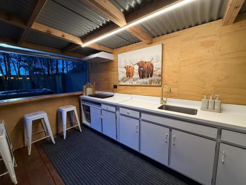 a kitchen with a sink and a counter with stools at Forest Hillside Glamping Retreat in Lochiel