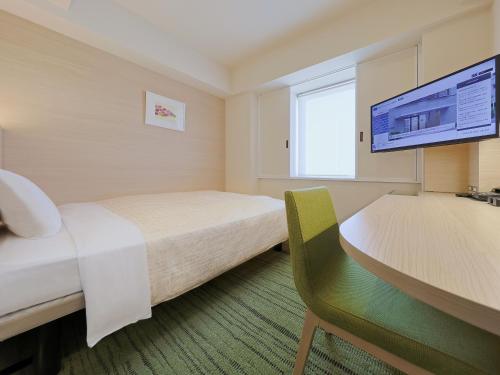 a hotel room with two beds and a desk and a tv at Keio Presso Inn Gotanda in Tokyo