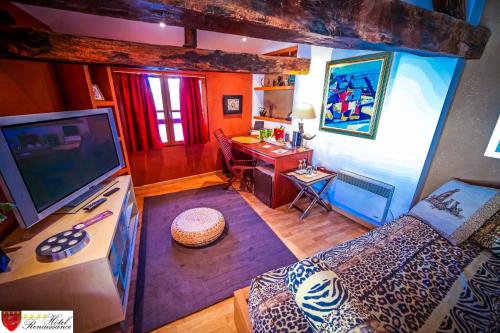 a living room with a couch and a desk with a television at Hôtel Renaissance in Castres