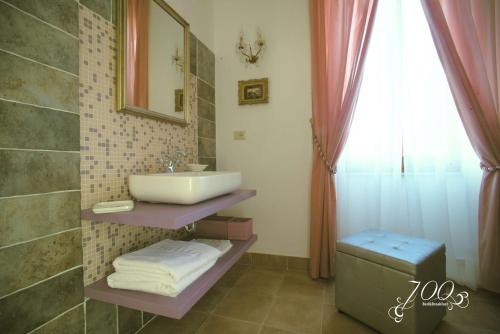 ein Bad mit einem Waschbecken, einem Spiegel und einem Fenster in der Unterkunft Luxury B&B '700 in Ascoli Piceno