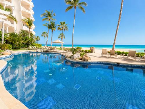 a swimming pool with palm trees and the beach at Mykonos Recently remodeled 1BR Beach Escape great view! in San José del Cabo
