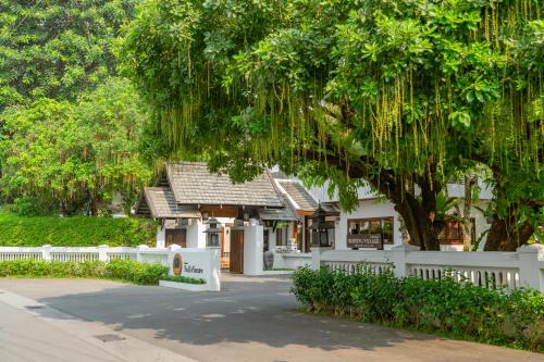 a white fence in front of a house with a tree at Rimping Village in Chiang Mai