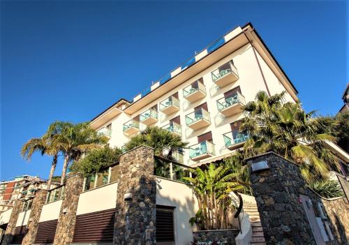 a building with palm trees in front of it at Hotel Ariston & Apartments in Varazze